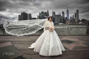 Bride in a flowing gown with veil overlooking the city skyline