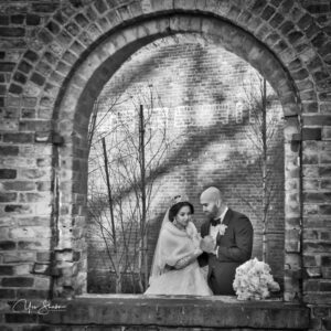 Bride and groom in a brick archway, sharing a quiet moment on their wedding day