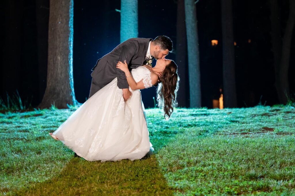 wedding couple dancing at night under a tree illuminated by lights in a park