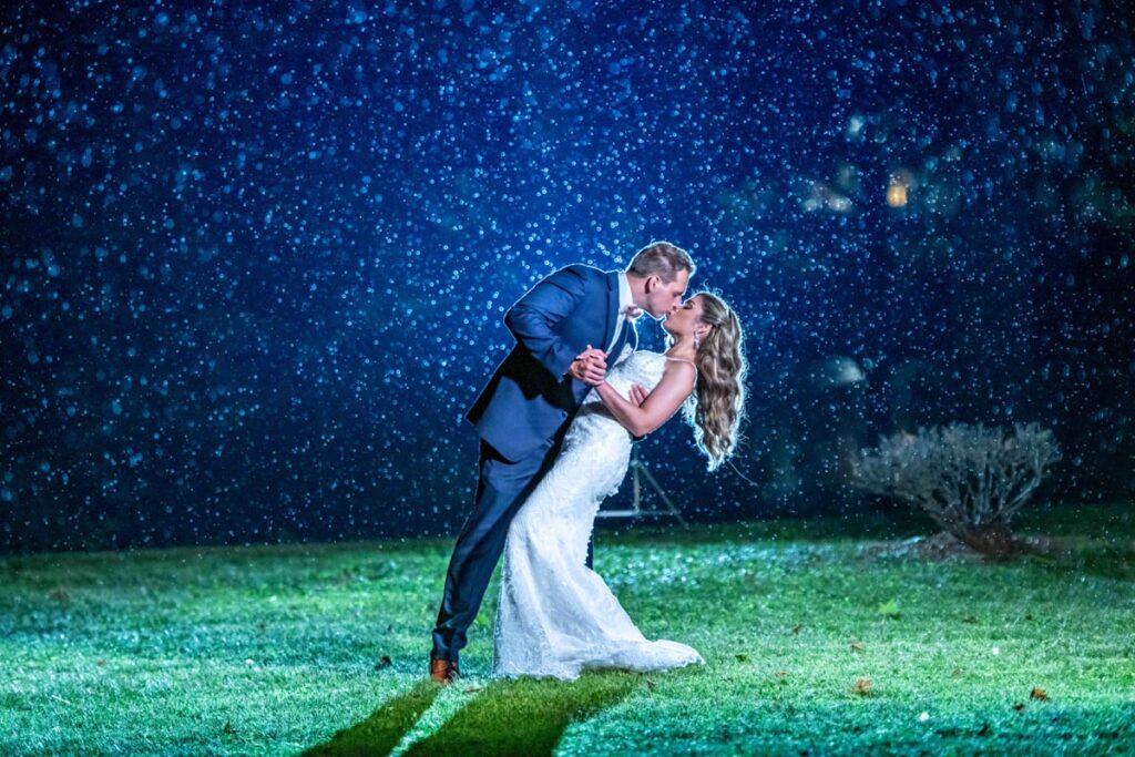 bride and groom dancing at night under a tree illuminated by lights in a park
