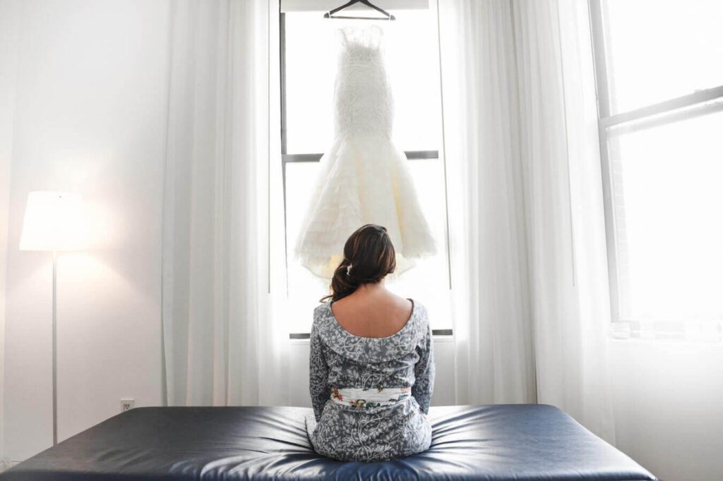 bride sitting in front of her wedding dress