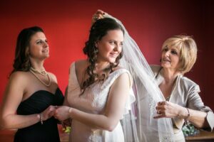 bride's mother putting a veil on her daughter's head
