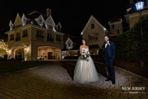 Bride and groom standing outside a large, elegant building at night