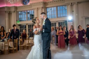 Bride and groom sharing their first dance at the wedding reception, surrounded by guests