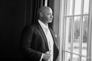 Groom standing by a window, looking out thoughtfully
