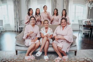 Bride and her bridesmaids in matching robes sitting and smiling together before the wedding