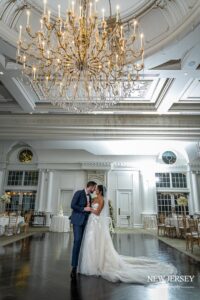 Bride and groom sharing a romantic moment under a grand chandelier in an elegant ballroom