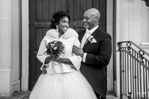 Bride and groom smiling at each other in front of a church doorway