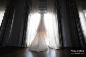 Bridal gown hanging in front of a large window, illuminated by natural light
