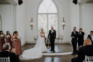 Bride and groom standing together at the altar during their wedding ceremony, surrounded by their bridal party