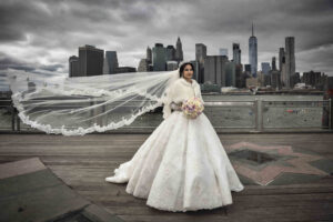 Bride in a flowing gown with veil overlooking the city skyline
